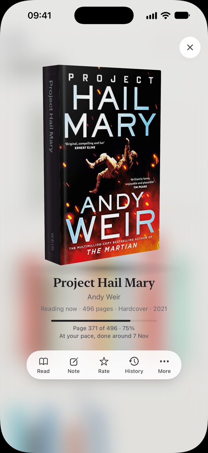 Project Hail Mary in your hand, the shelves soft behind it
